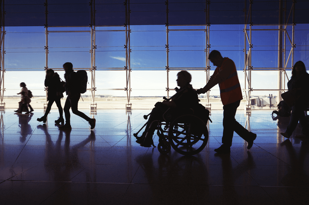 Photograph of a disabled passenger travelling through the airport, while using a wheelchair.