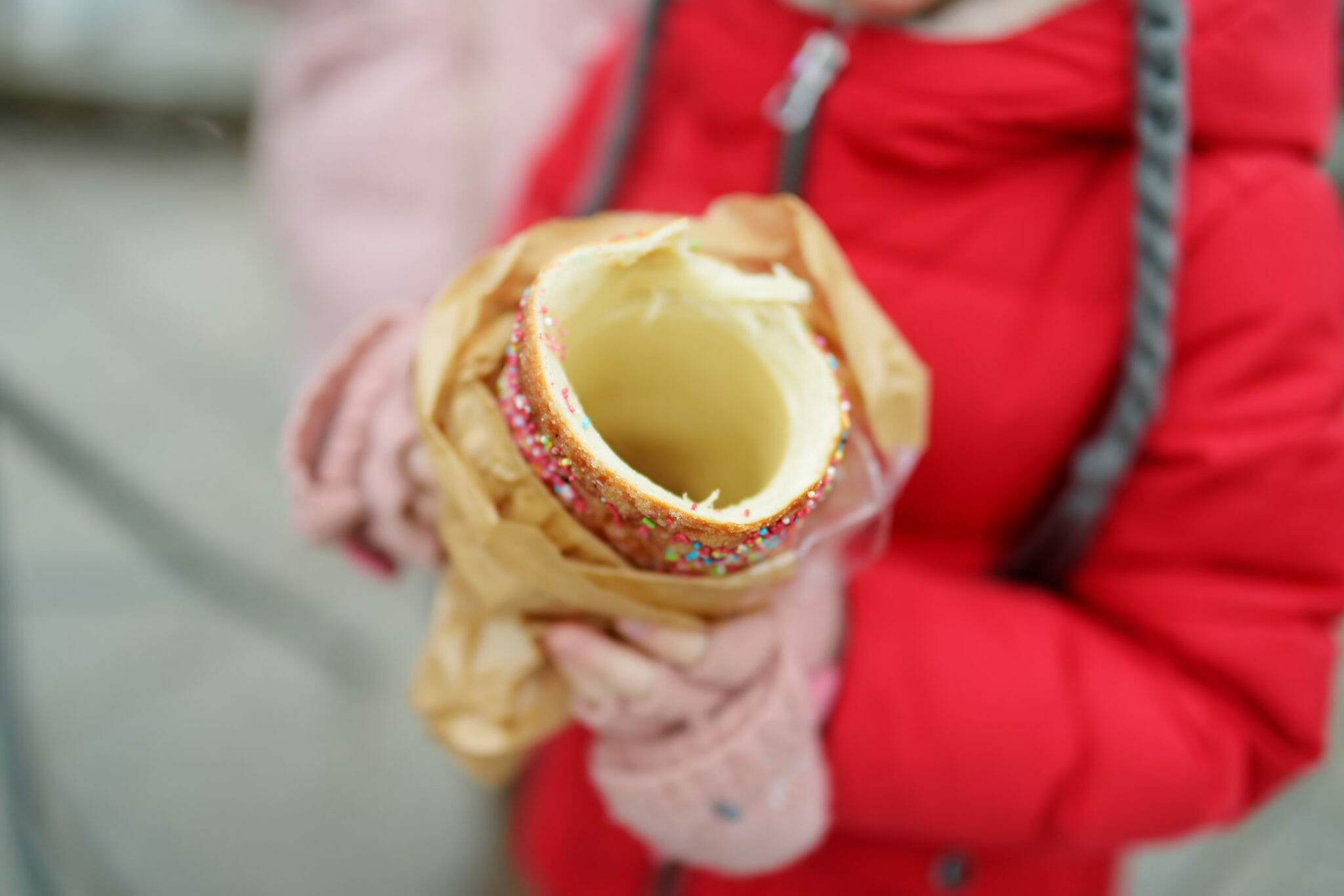 girl eating Czech trdelnik on traditional Christmas fair in Vilnius, Lithuania. Child enjoying sweets, candies and gingerbread on Xmas market.