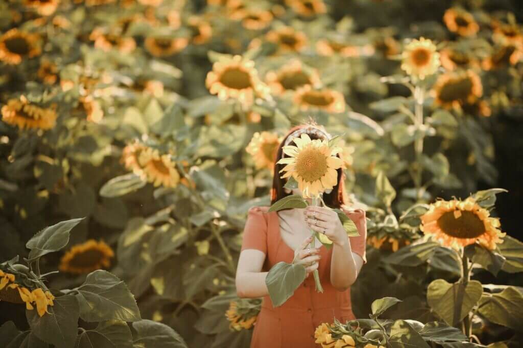 girl holding a sunflower in a field
